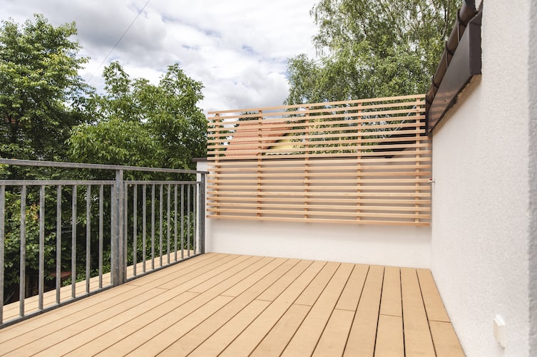 Terrasse mit Holzboden und Rankgerüst.